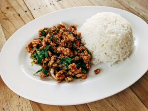 stir fried thai basil with minced pork and rice on oval ceramic plate
